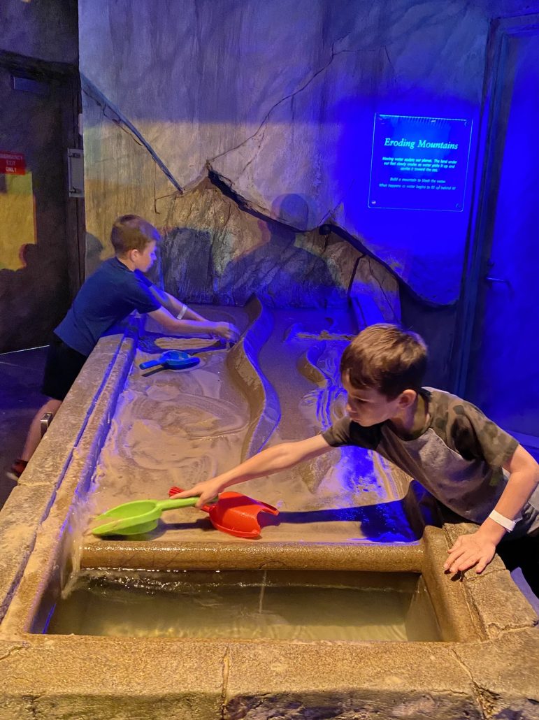 Two kids digging in sand at an exhibit at COSI Science Center in downtown Columbus, Ohio.