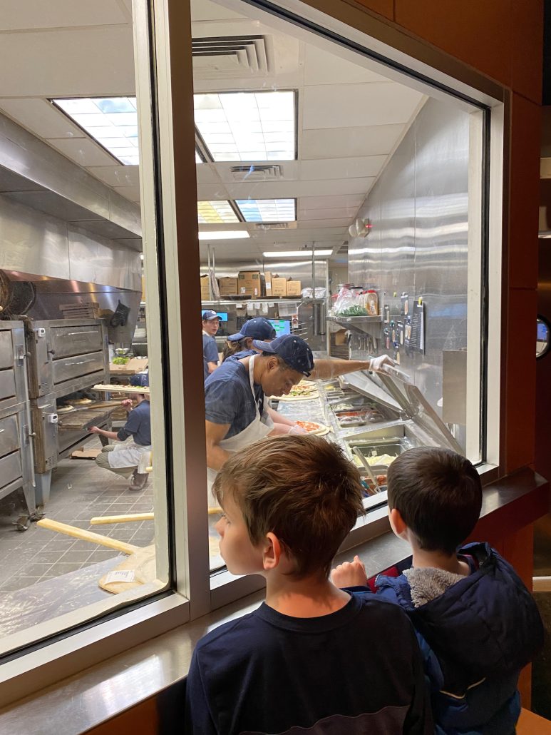 Two boys watching pizza be made at Dewey's Pizza.