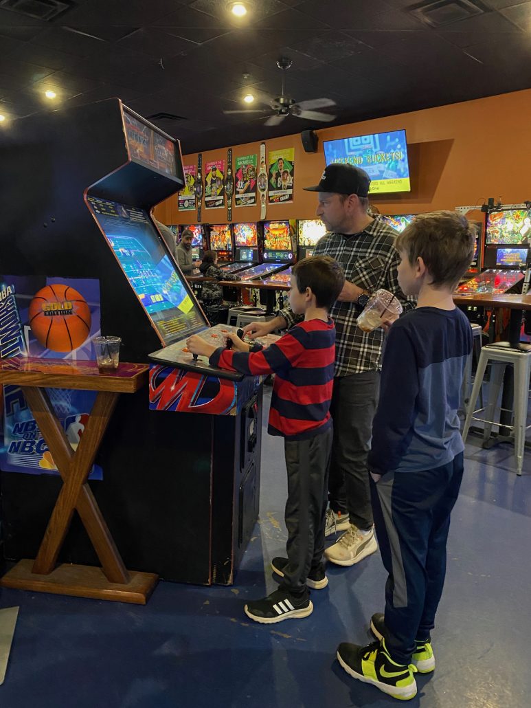 Two boys and a father playing video games at Level One Arcade in Worthington, Ohio.