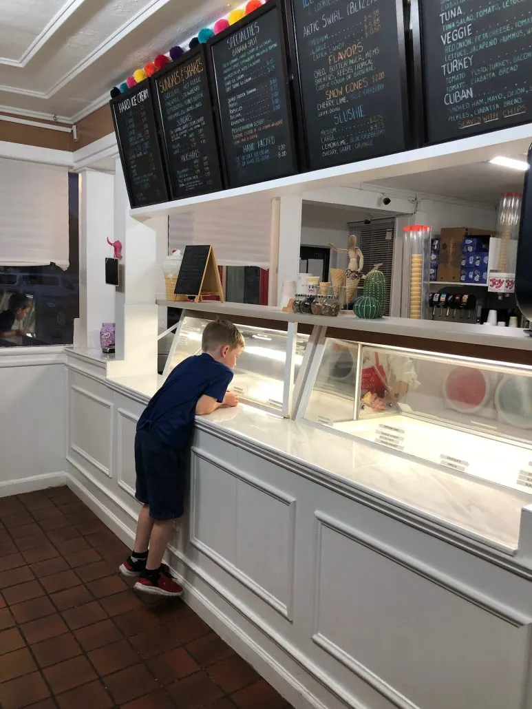 A boy looking over the counter at the ice cream flavors at Mona's Eats and Treats.