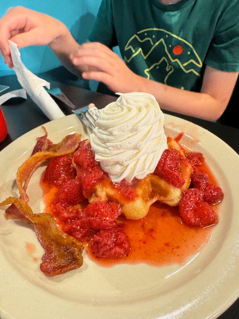 A liege waffle with strawberries and whipped cream on top at Wake Up and Waffle.