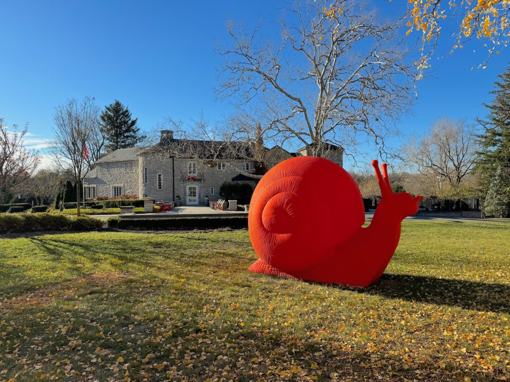 A bright orange snail sculpture on the front lawn of the Dublin Arts Council in Dublin, Ohio.