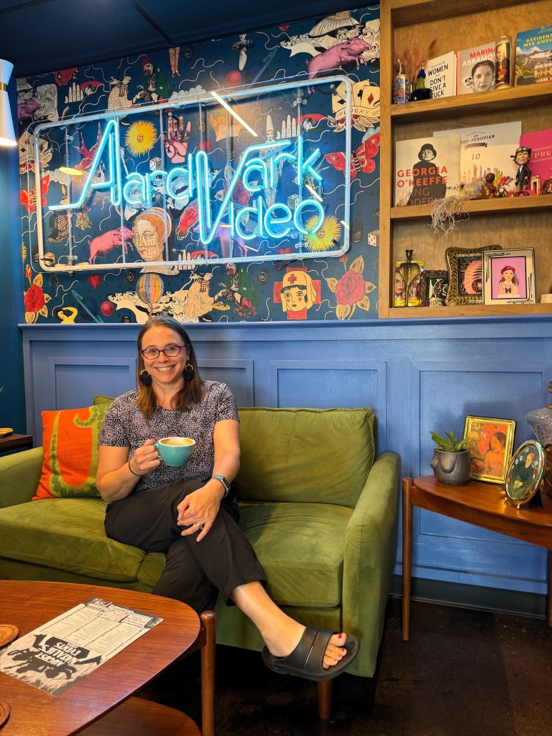 A woman sitting on a couch at. Royal Flamingo with a cup of coffee.