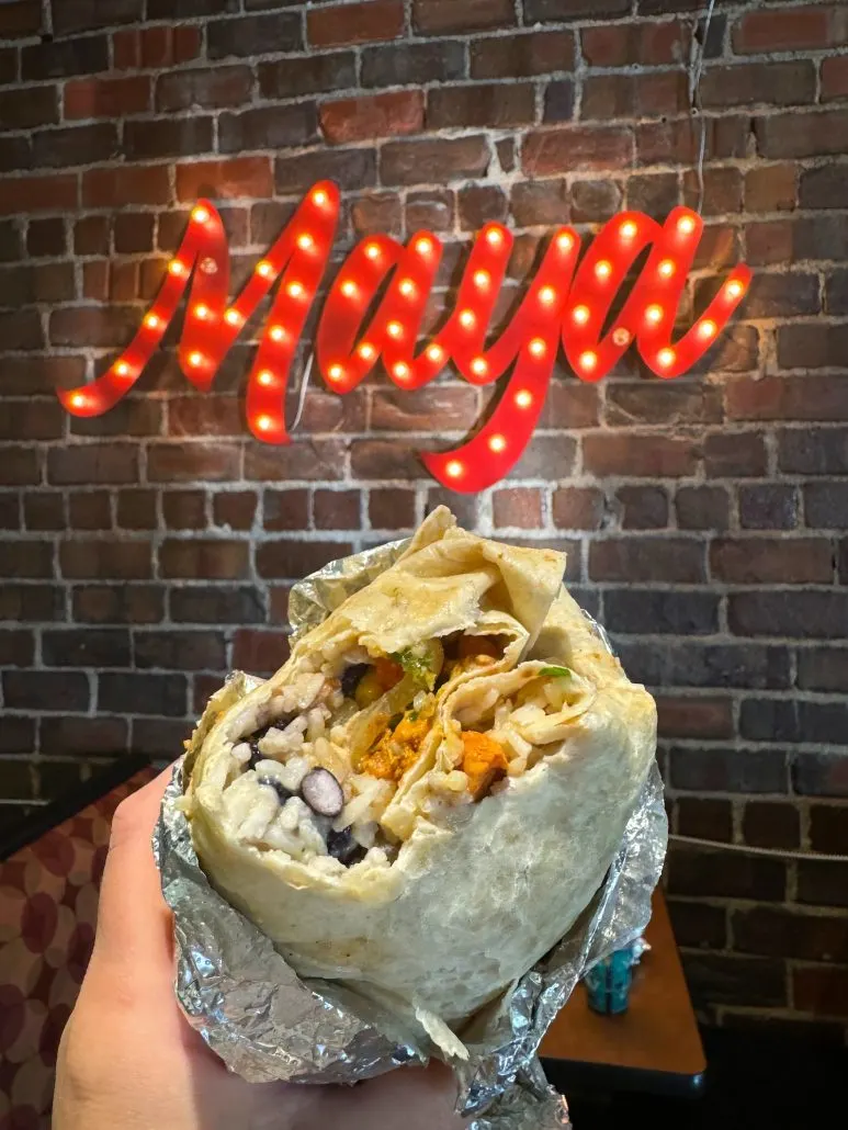 A burrito in front of a sign that says "Maya".