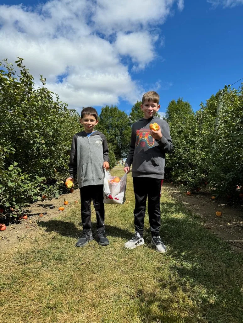 Two boys holding up a bag of apples they picked in the orchard in Plain City.