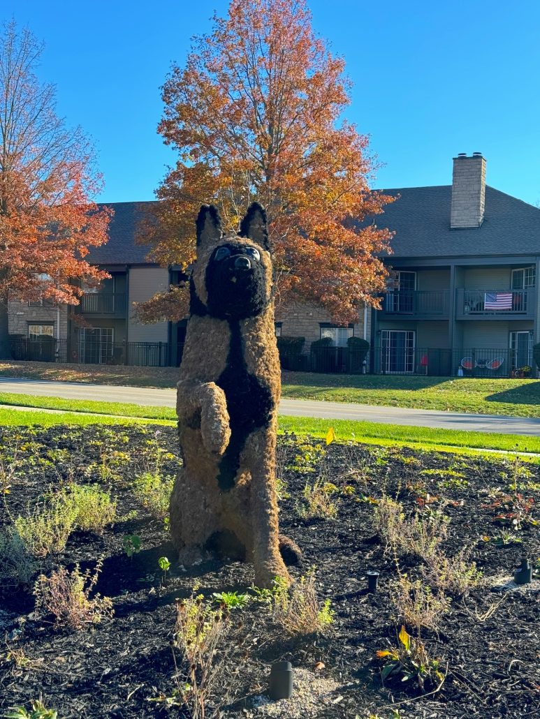 A dog topiary with its paw raised.