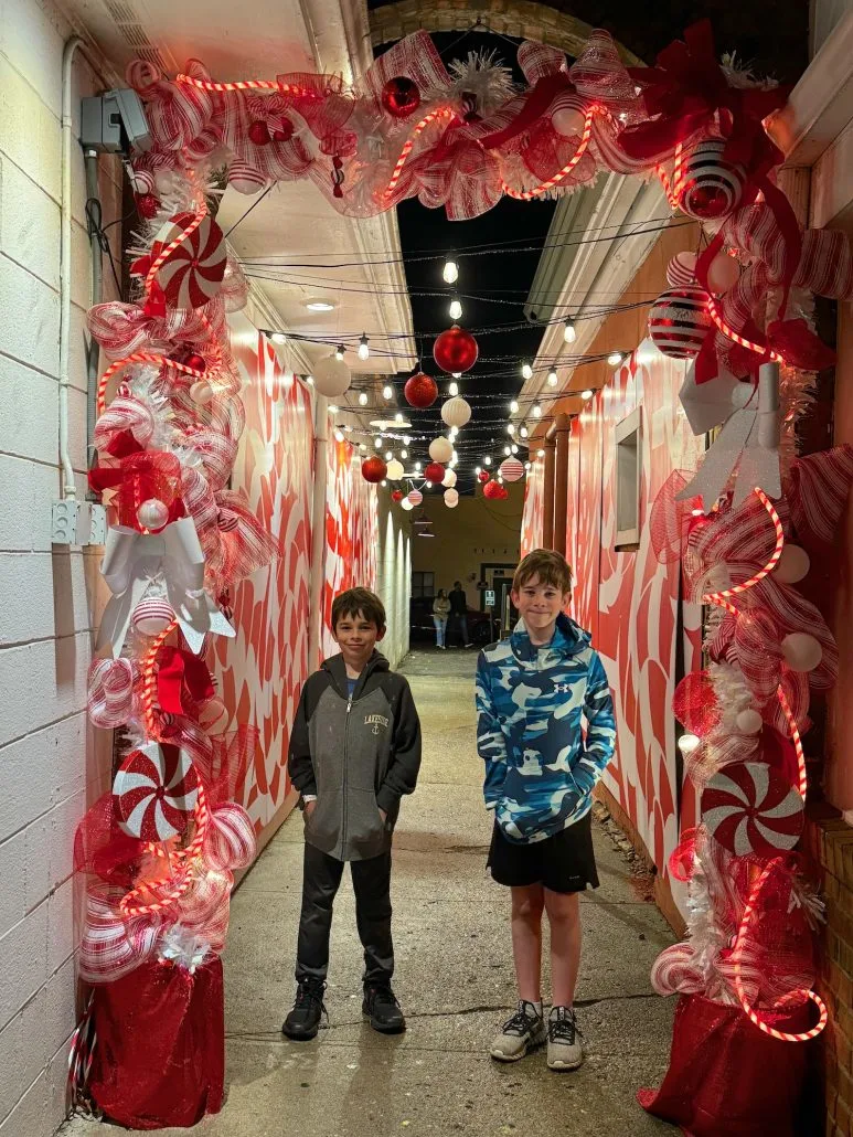 Two boys standing in a candy cane decorated alleyway in Old Worthington.